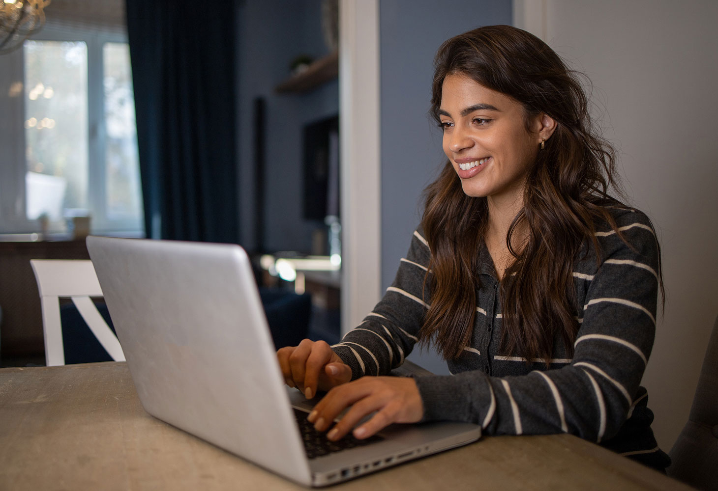 female student smiling while using computer at table.