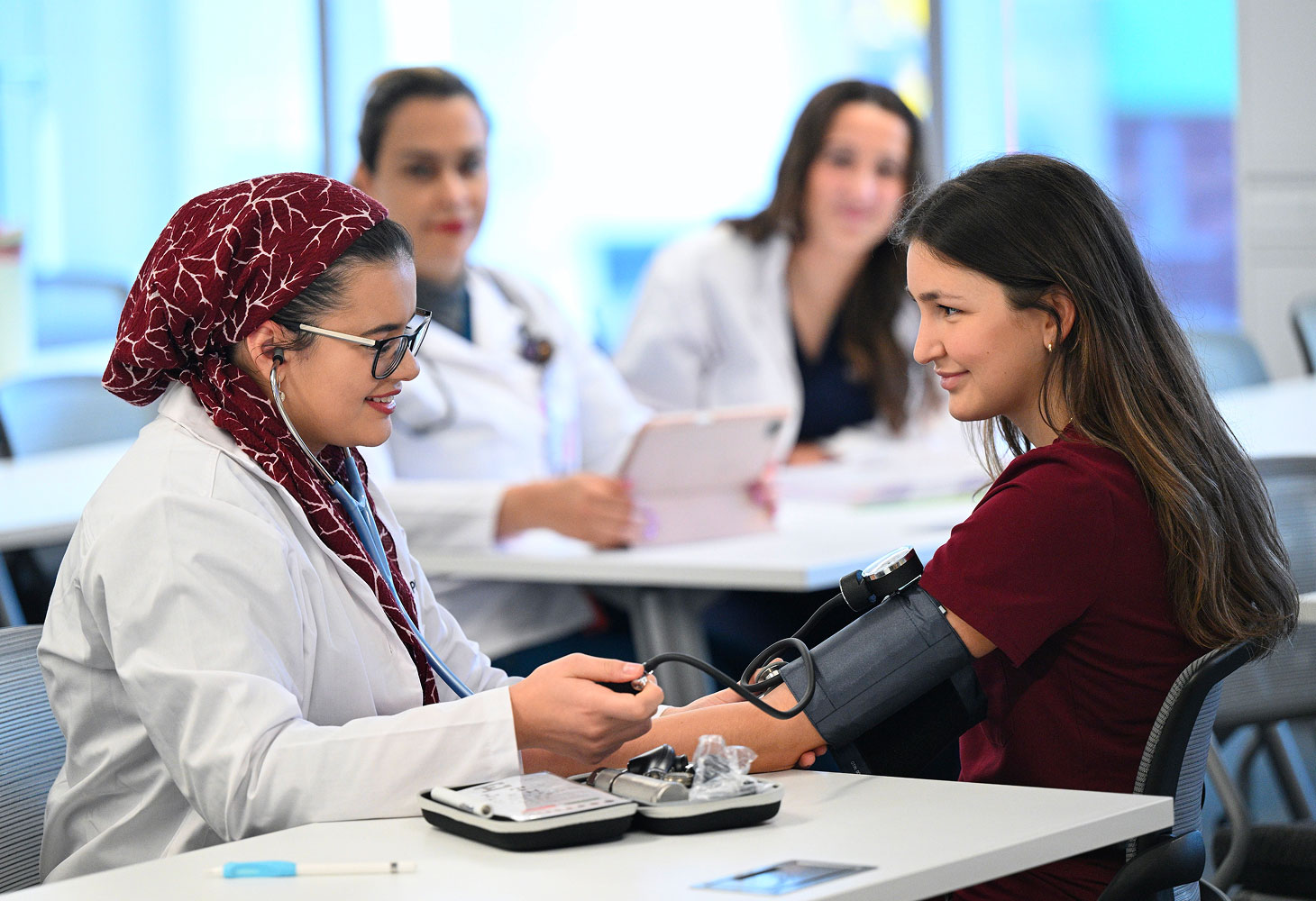 student examining wrist of fake patient in class.